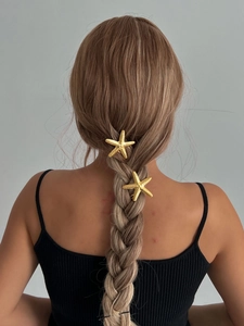 Detailed view of two gold starfish hair clips styled in a braided hairstyle for women