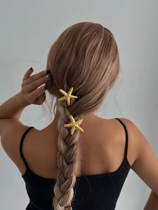Close-up of golden starfish hairpins with realistic texture on a female hairstyle