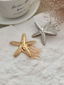 Detail view of gold and silver starfish hair pins with textured metallic finish