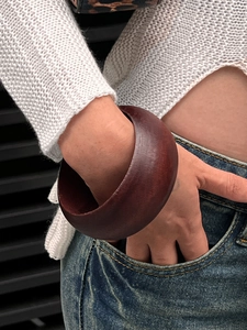 Detail of wide red-brown wooden bangle showing smooth matte finish and retro texture