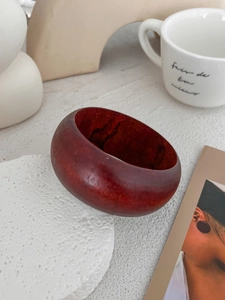 Macro detail of deep red wooden wide bangle showcasing natural grain and smooth texture