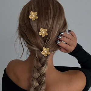 Three elegant matte gold flower hair pins with pearls styled in a woman's braid