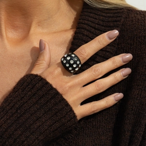 Detail shot of a black wide dome ring with sparkling rhinestones on an autumn sweater background