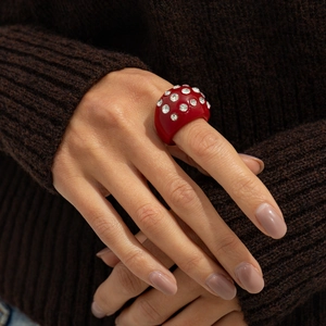 Detail of red chunky resin ring with sparkling rhinestones worn over a brown sweater