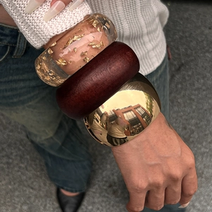 Three-piece chunky bangle set featuring gold leaf resin, dark wood, and polished metal