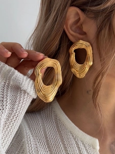 Detailaufnahme der unregelmäßigen goldfarbenen Ohrringe mit flüssigem Metall-Effekt
