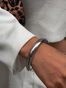 Polierter silberner breiter Armreif am Handgelenk des Models im modernen Stil