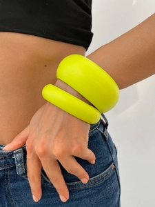 Nahaufnahme matter neon-gelber Kunststoff-Armreifen am Handgelenk im Modestil