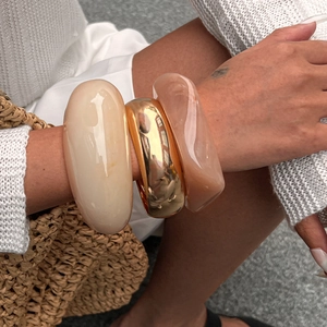 Three-piece set of chunky bangles in gold metal, cream resin, and amber finishes