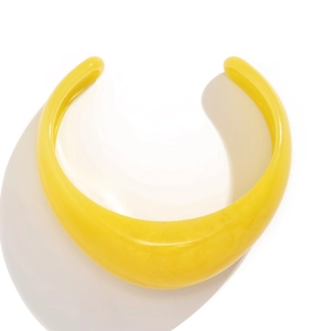 Detail of a bright yellow resin cuff bracelet with a smooth marble-like texture finish