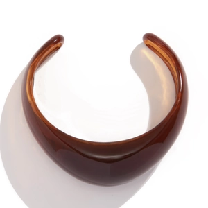 Macro shot of thick amber translucent resin collar necklace with irregular C-shaped design