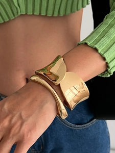 Dettaglio di polsini e bracciali curvi dorati lucidi in stile punk sul polso di un modello