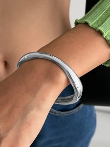 Dettaglio di un ampio bracciale rigido in argento lucido con finitura a specchio e cerniera