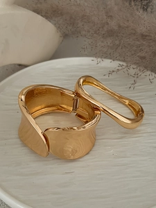 Dettaglio macro del bracciale largo concavo dorato con finitura lucida e cerniera