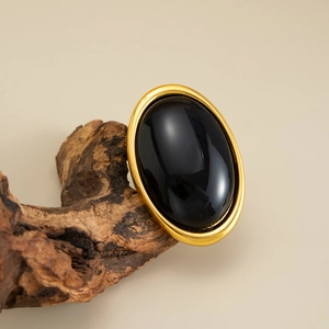 Detailed view of an oval black resin gemstone set in a thick gold vintage geometric ring