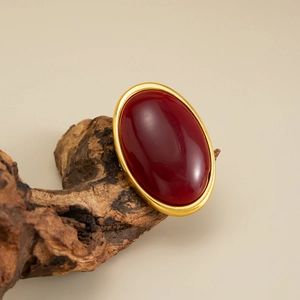 Macro detail of vintage gold oval ring with deep red gemstone on natural wood base