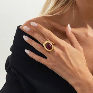 Close-up of a model wearing a gold vintage ring with a large oval dark red gemstone