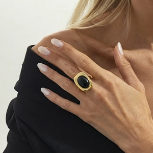 Close-up of vintage gold chunky ring with oval black gemstone on model's hand