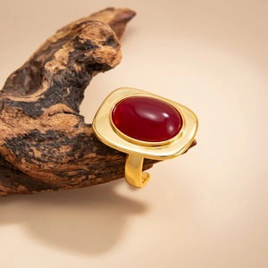 Detail of vintage gold ring with large oval red gemstone on natural wood display