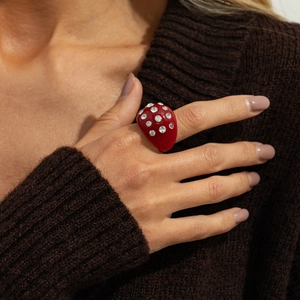 Detail of red resin ring with sparkling rhinestones worn against a brown sweater