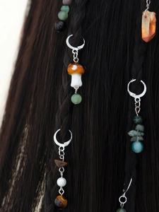Macro detail of ethnic style hair pendants with mushroom and crystal stones on braids