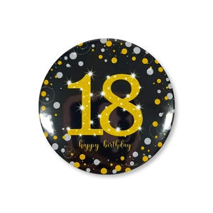 Macro detail of 18th birthday tinplate badge with gold glitter text on black background