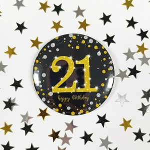 Close-up of a 21st birthday badge with gold happy birthday text on a black base