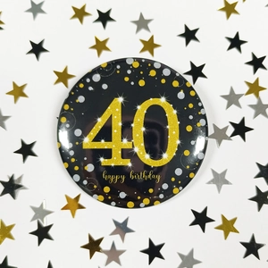 Detail of 40th birthday tinplate badge with gold number 40 and confetti party props