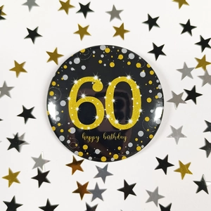 Detail of 58mm black and gold 60th birthday badge with sparkling glitter and confetti