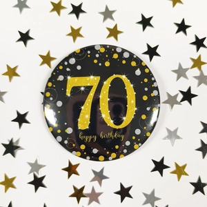 Detailed view of black and gold 70th happy birthday badge with festive star confetti