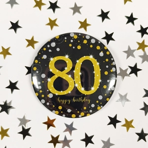 Close-up of 80th happy birthday pin badge with gold dots on a festive background