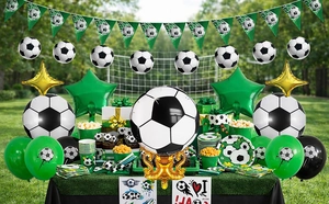 Soccer theme party set with foil balloons, flags, and tableware on green grass