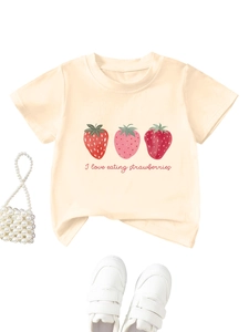 Gros plan sur l'imprimé fraise et la typographie rose d'un t-shirt enfant en coton crème