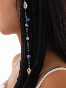 Detailed view of bohemian hair chain with natural shells and colorful beads on braid
