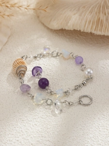 Detail of beach hair chain with seashells, purple gemstones, and white pearls