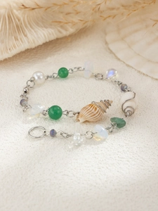 Macro detail of ocean style chain with conch shells, pearls and green aventurine beads