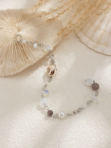 Detail of seashell and natural stone fringe hair chain with pearls on white texture