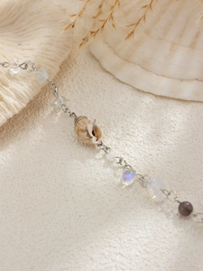 Detailed macro shot of beach hair chain with natural seashell and iridescent beads