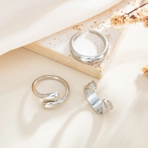Three-piece silver metal ring set featuring minimalist wave and teardrop open designs