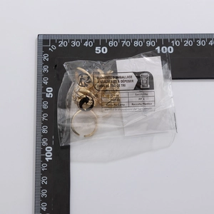 Detail of gold hollow chain ring and minimalist band in transparent packaging