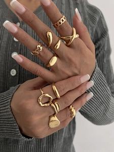 Close-up of 10-piece gold geometric ring set styled on model with chain and lava textures