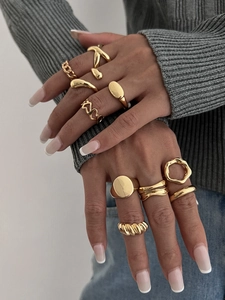 Macro view of 10 piece gold geometric rings set styled on model with knitwear