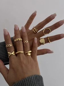 Close-up of 10-piece gold geometric ring set with heart and chain patterns on model's hand