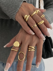 Close-up of a 10-piece gold geometric ring set styled on fingers with a casual outfit