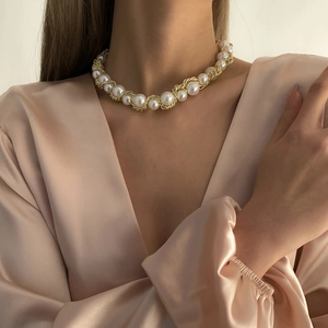 Elegant gold twisted chain and pearl necklace worn on a champagne silk garment