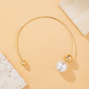 Detail of gold choker with white pearl and metal beads on a stone background
