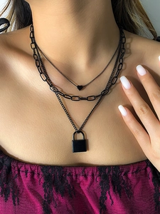 Detail of triple-layer black necklace with paperclip chain, heart and lock charms