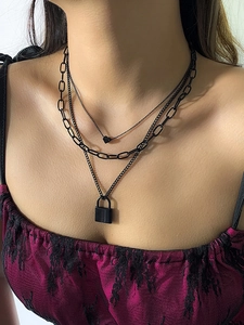 Close-up of punk style layered black necklace with heart pendant and lock detail