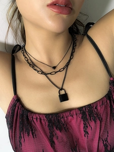 Close-up of layered black punk necklaces with heart and lock charms on model