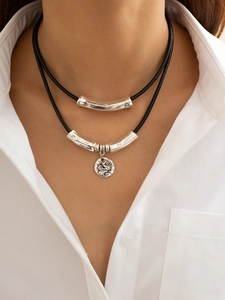Detail of a double-layer necklace with silver curved tube and vintage relief coin pendant